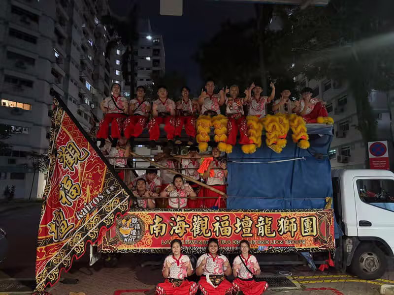 Troupe gathered on the decorated lorry at night with lion heads and banners