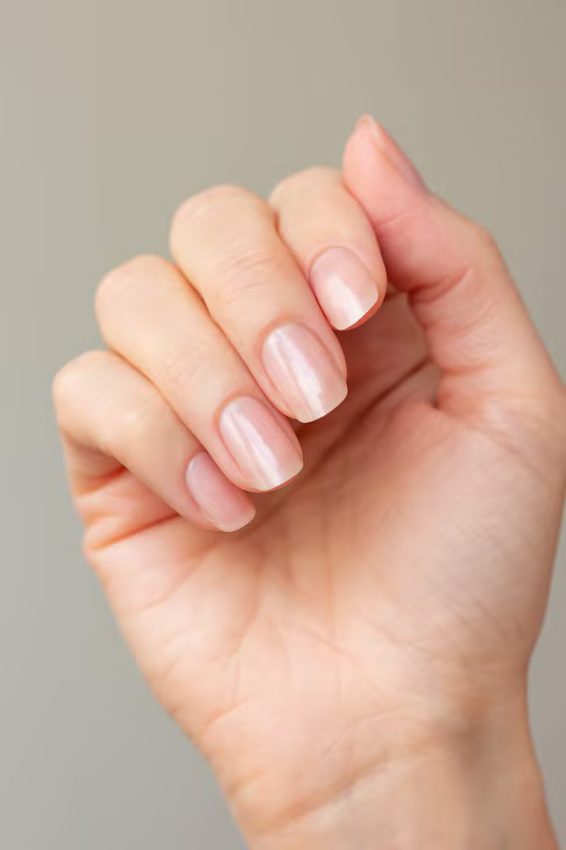 Nail technician carefully shaping and finishing a client's nails