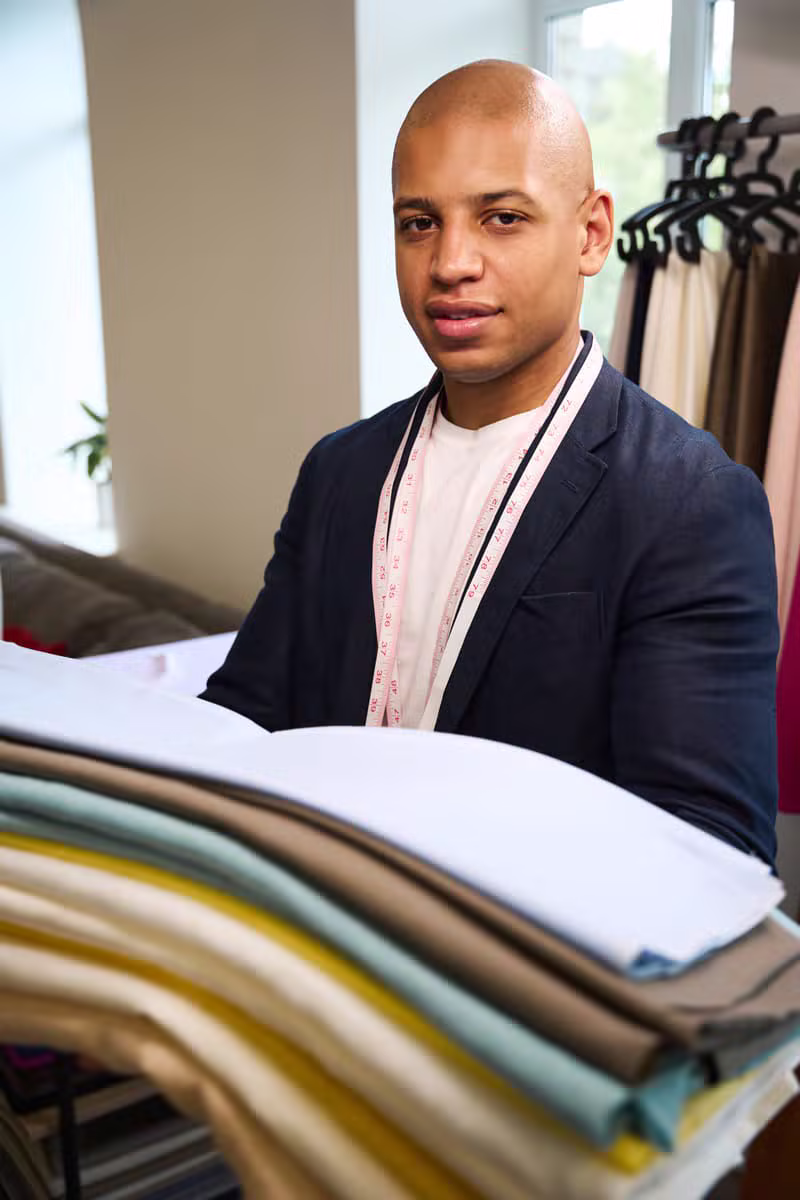 Male tailor displaying premium fabric for Nigerian menswear