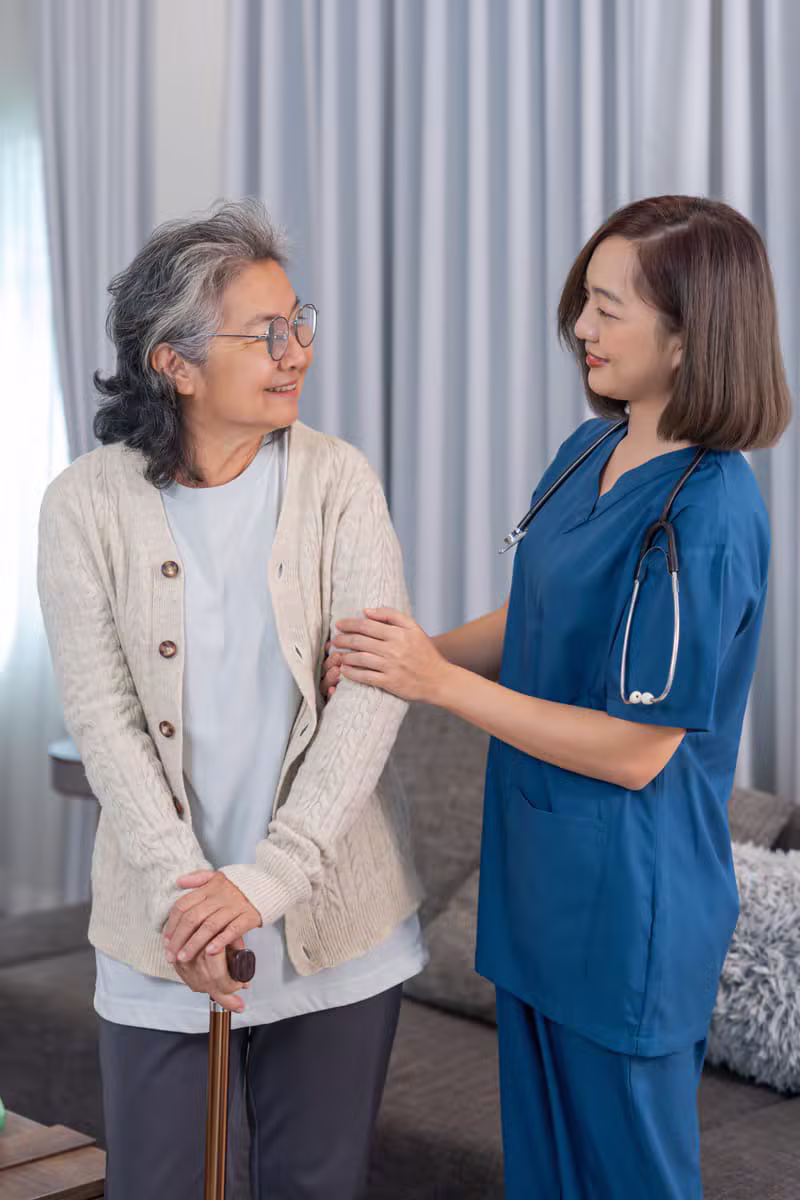 Auxiliaire de vie et personne âgée souriant ensemble à domicile