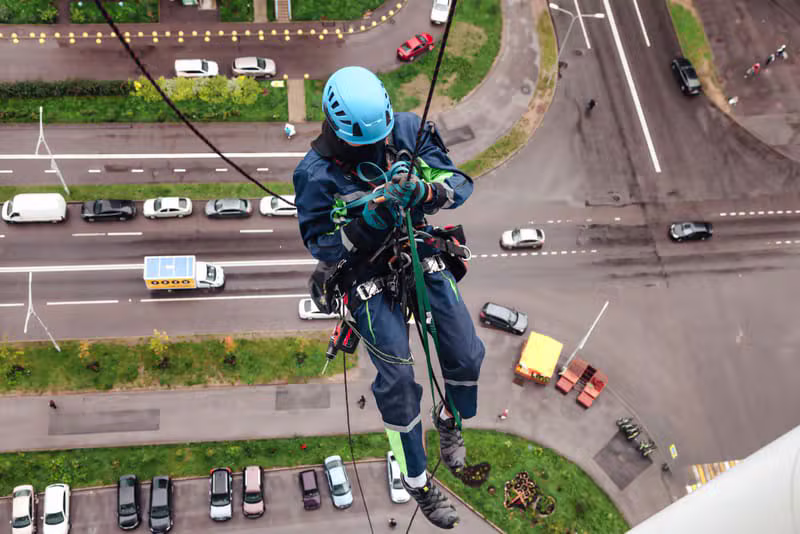 Técnico de acesso por corda trabalhando na fachada de um edifício