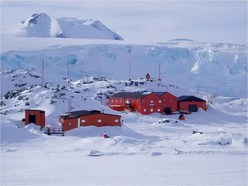 Base antártica con construcciones rojas sobre el paisaje nevado y los glaciares