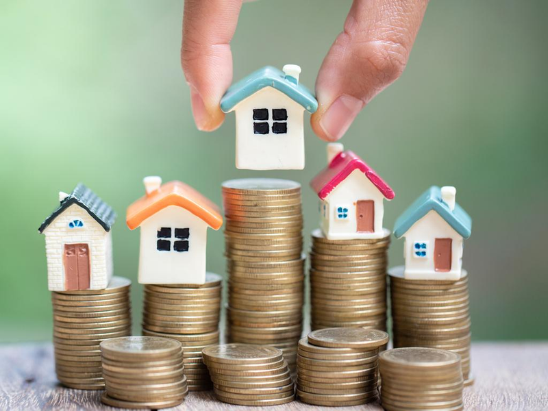 Miniature houses on stacks of coins