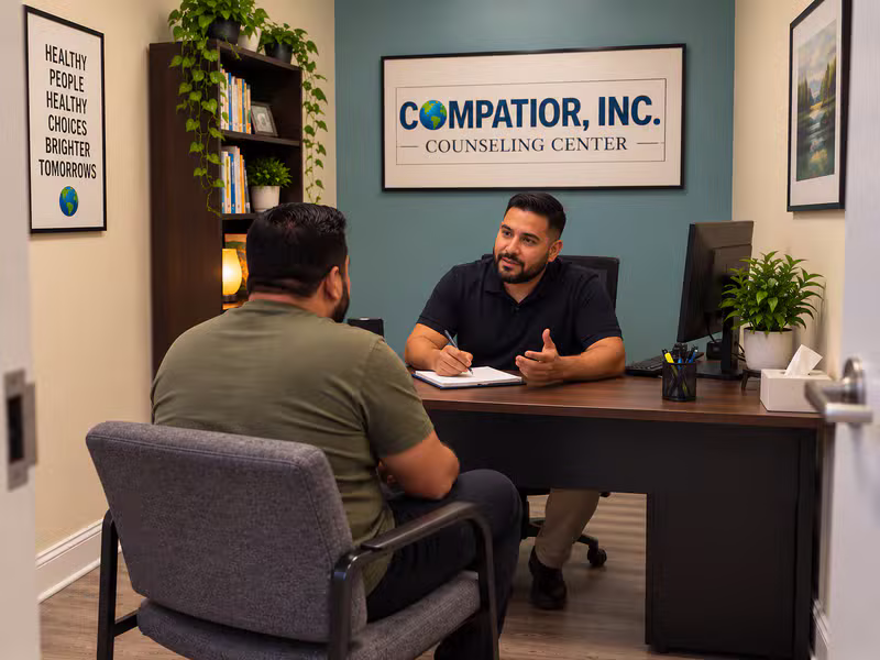 A counselor speaking with a client in a warm, welcoming counseling office at Compatior Counseling Center