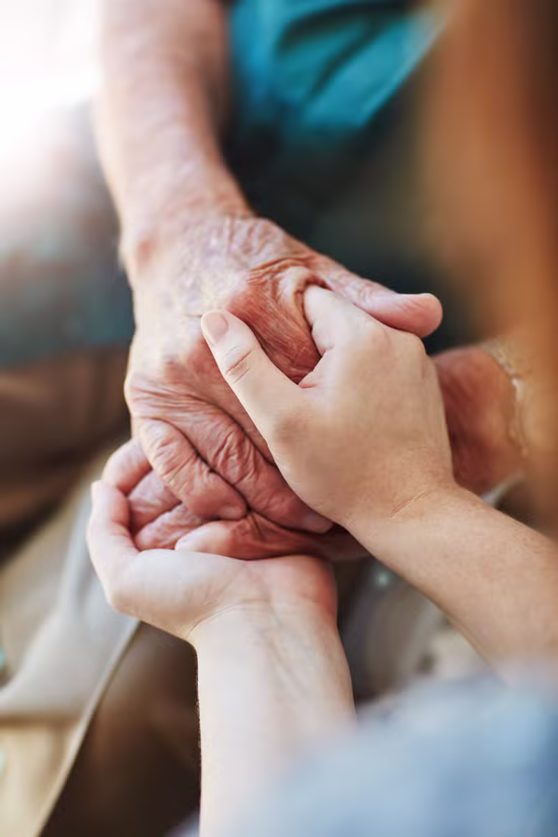 Caregiver warmly holding hands with a senior client