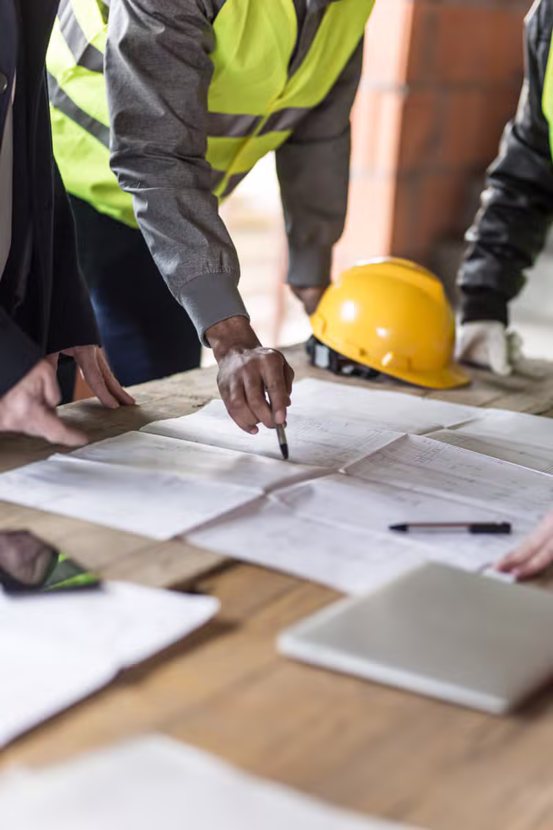 Architectes et ouvriers examinant un plan de construction