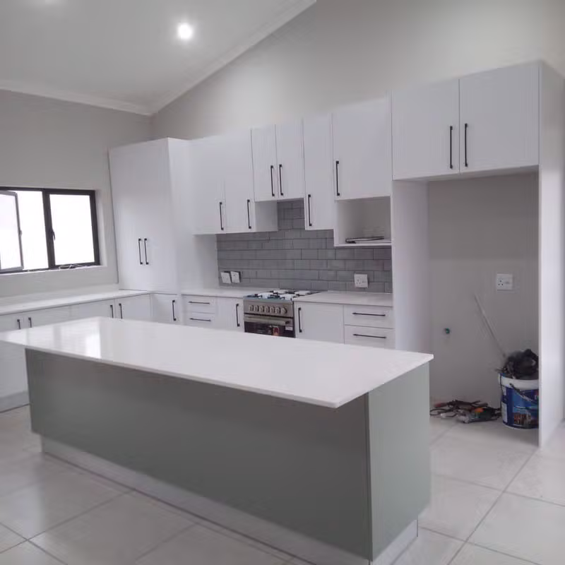 Modern kitchen with white cabinets and a sage green island by Dumakwizulu Group