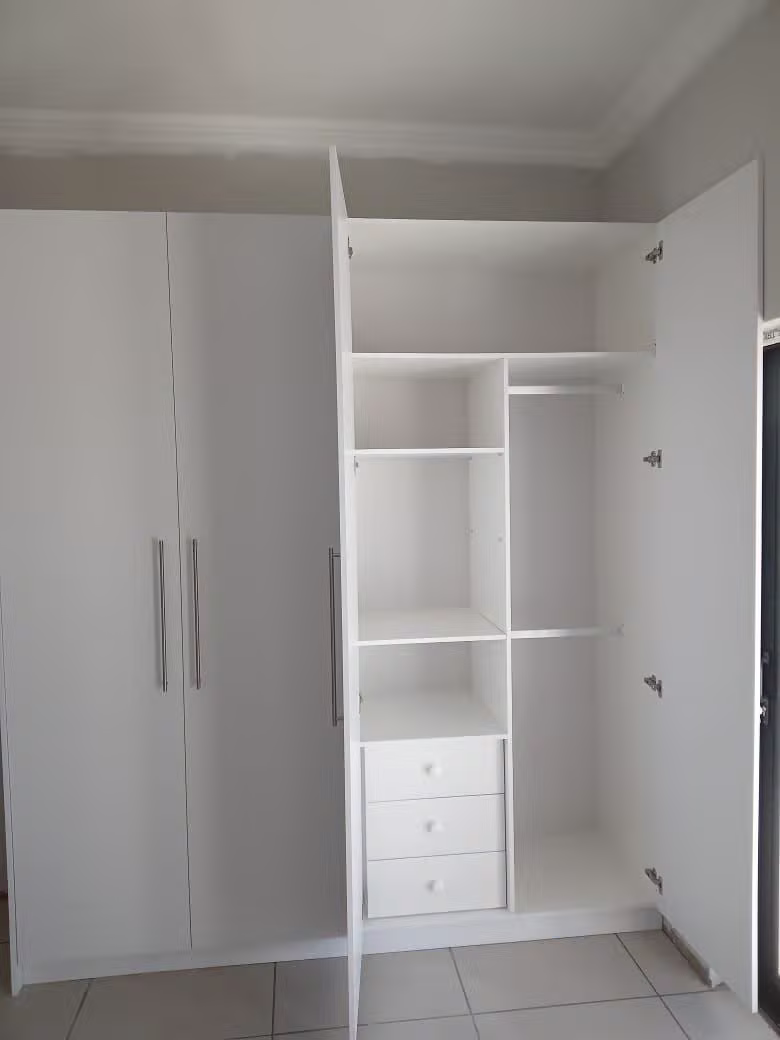 White built-in wardrobe with drawers and shelving by Dumakwizulu Group
