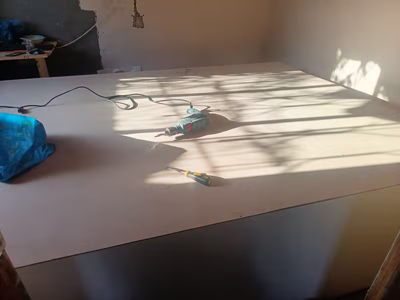 Power drill and hand tools on an MDF cabinetry panel