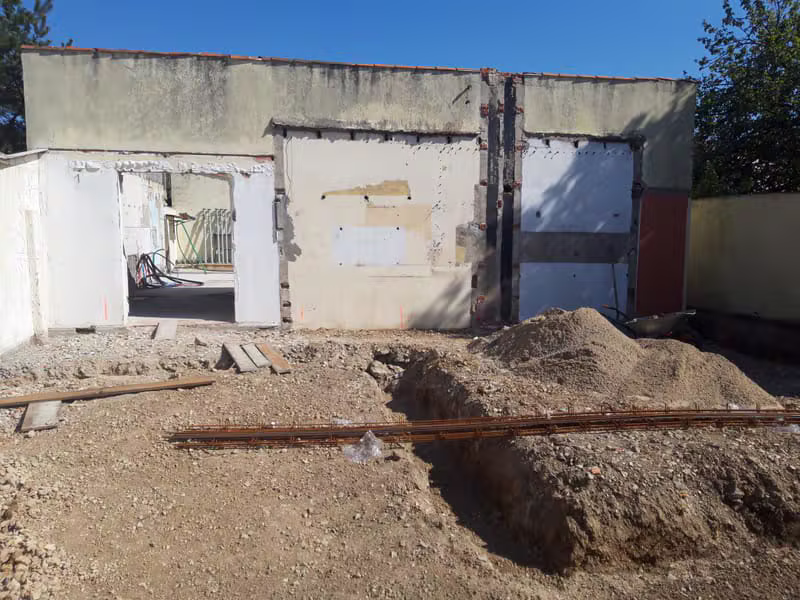 Travaux d'extension d'une maison avec ouvertures de façade et terrassement extérieur