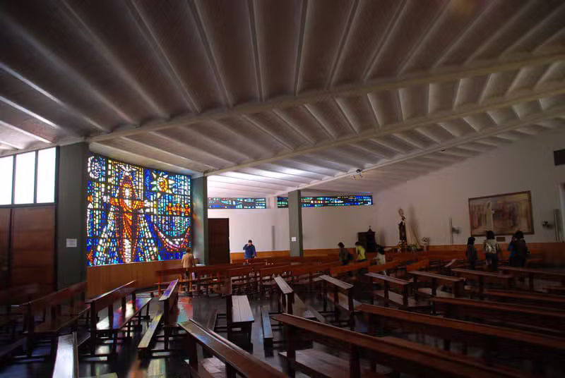 Interior del templo de San Pío X con la gran vidriera del Cristo y los bancos de la asamblea