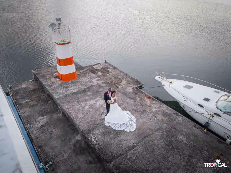 Mariés posant sur le môle au pied du phare, vus du drone