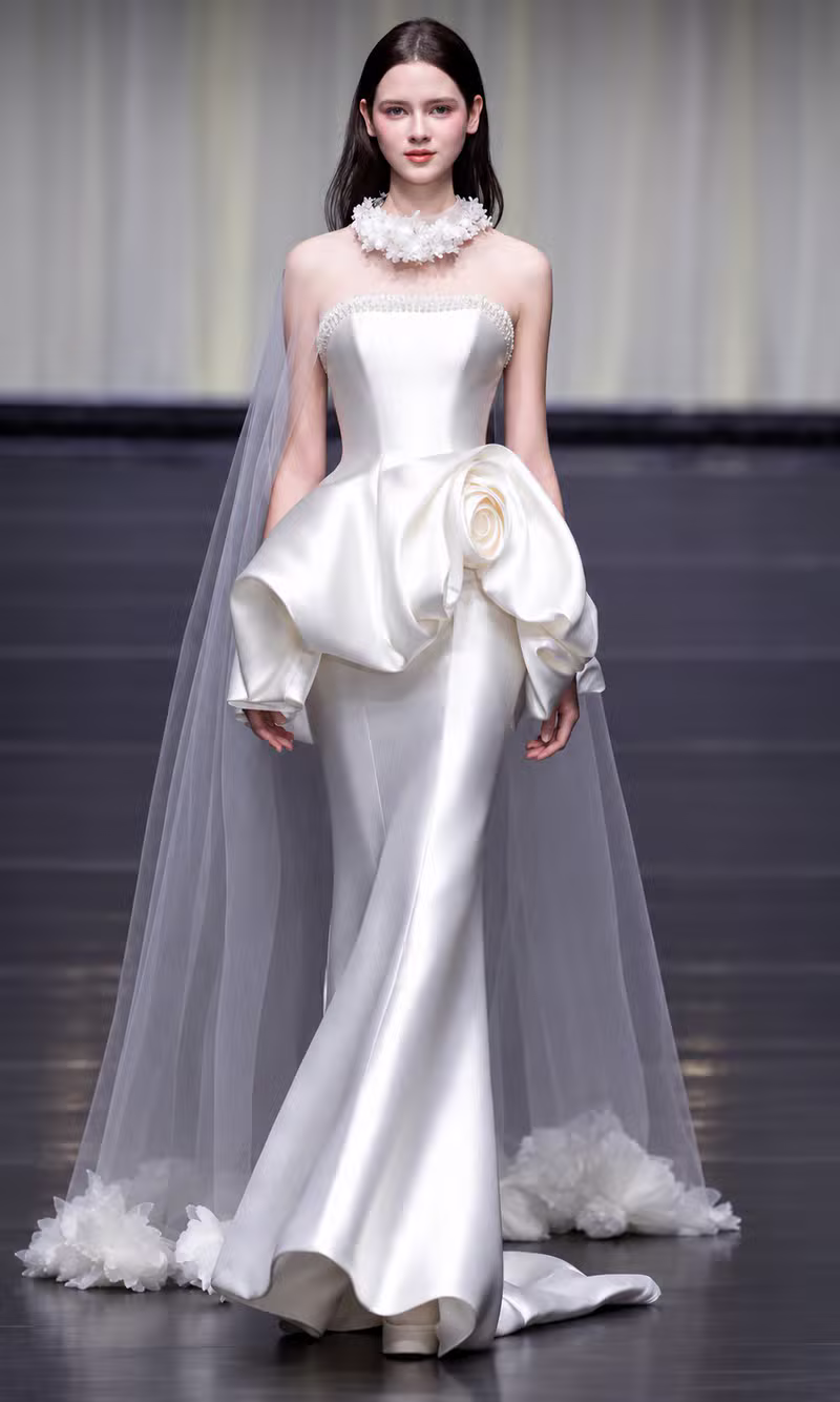 Ivory satin mermaid couture gown with a sculptural rose peplum and tulle cape