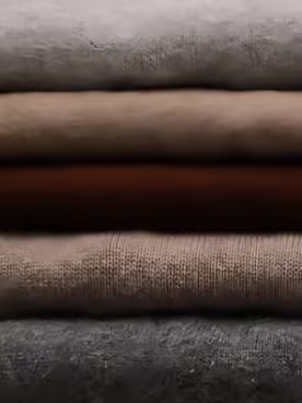 Layers of ivory silk-wool, camel wool, cocoa-brown silk satin, greige tweed and charcoal cashmere stacked in the atelier
