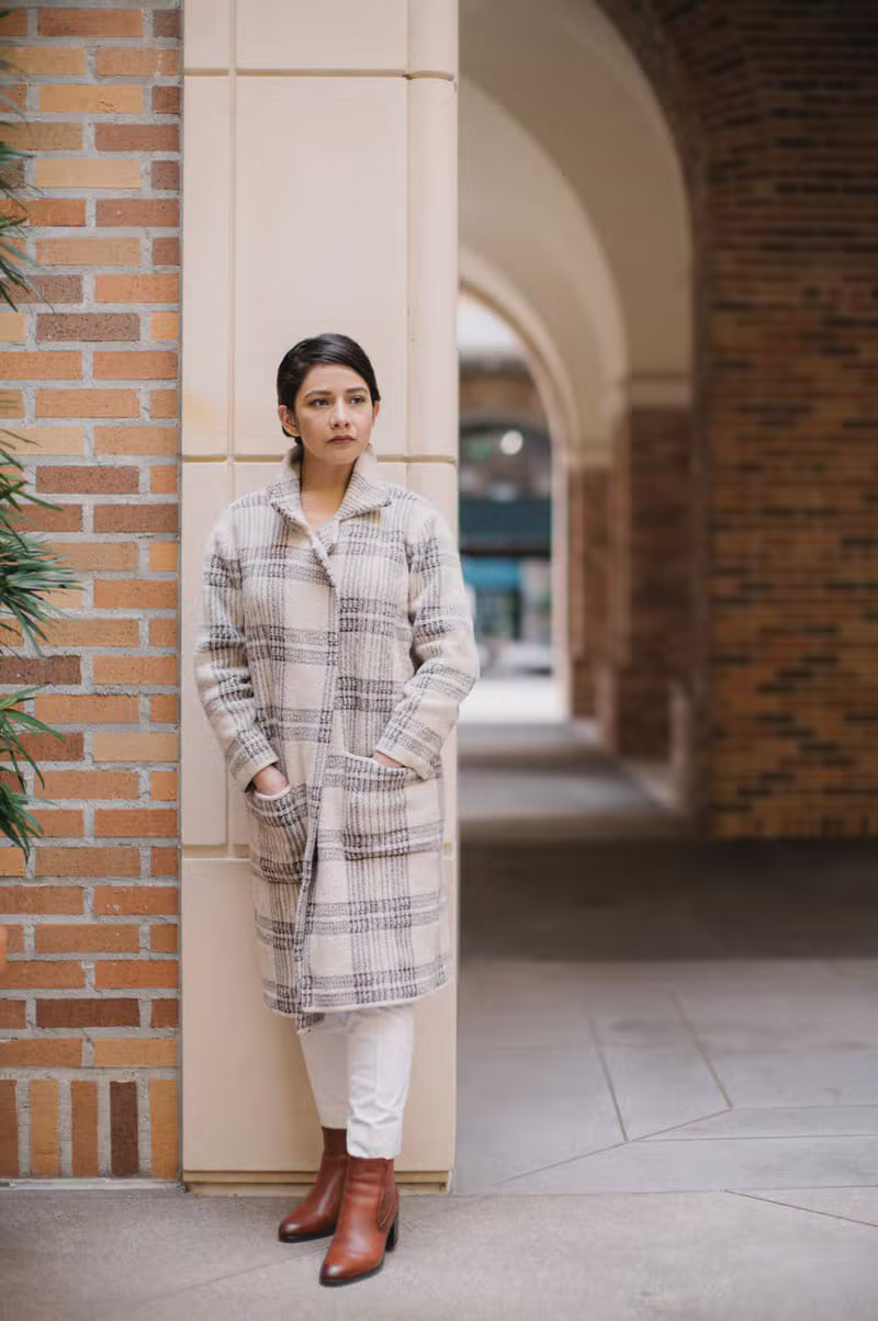 A woman standing calmly in soft neutral outerwear