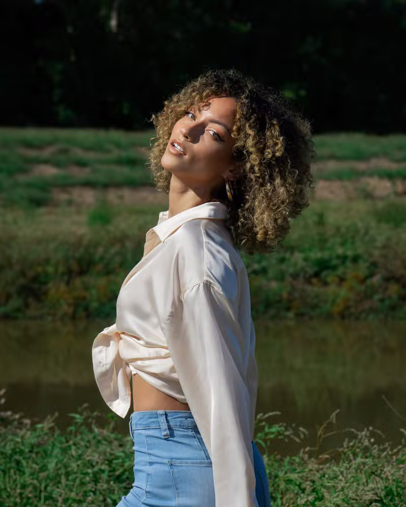 A woman wearing a silk blouse in soft daylight