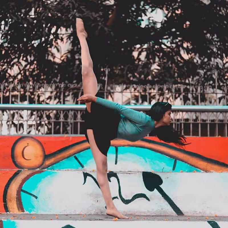 Contemporary dancer performing a standing split against a graffiti wall