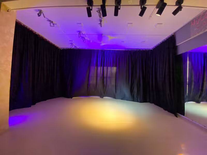 Black-curtain studio stage lit with a purple and blue mood wash