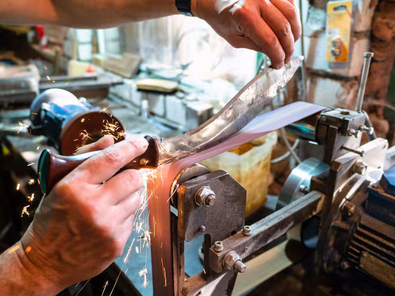 Bladesmith grinding a knife edge in the A1 workshop