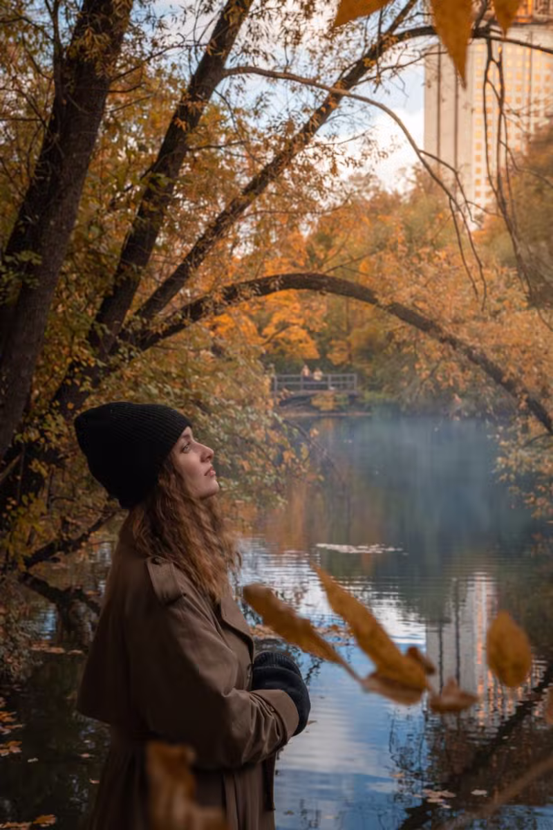 Eine Frau beobachtet still die Herbstlandschaft am Wasser