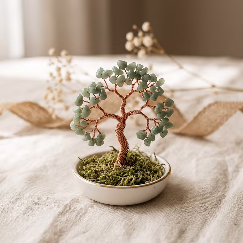 Mini arbolito de la vida en cuenco de cerámica blanca con borde dorado, con piedras de jade verde y musgo sobre lino crema