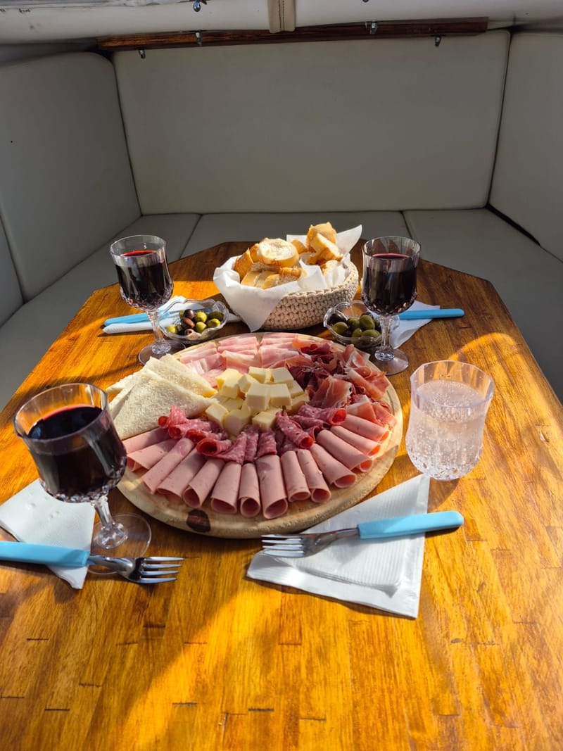 Mesa de catering a bordo con picada criolla, vinos y delicatessen dulces