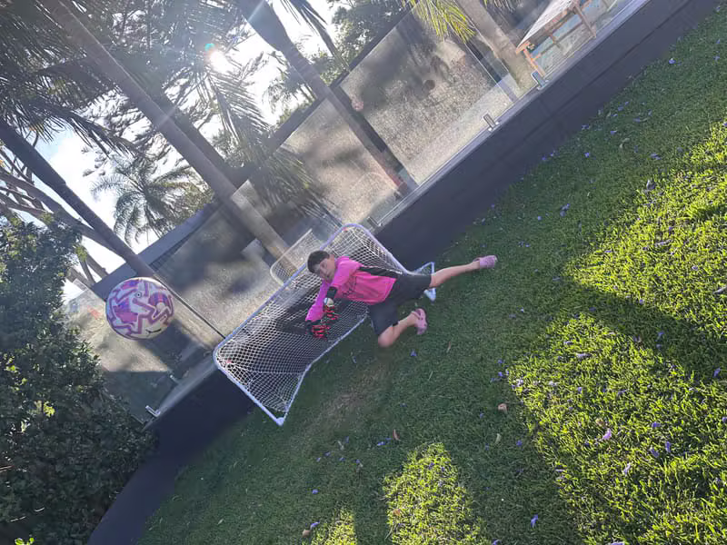 Young goalkeeper diving to make a save in football boots