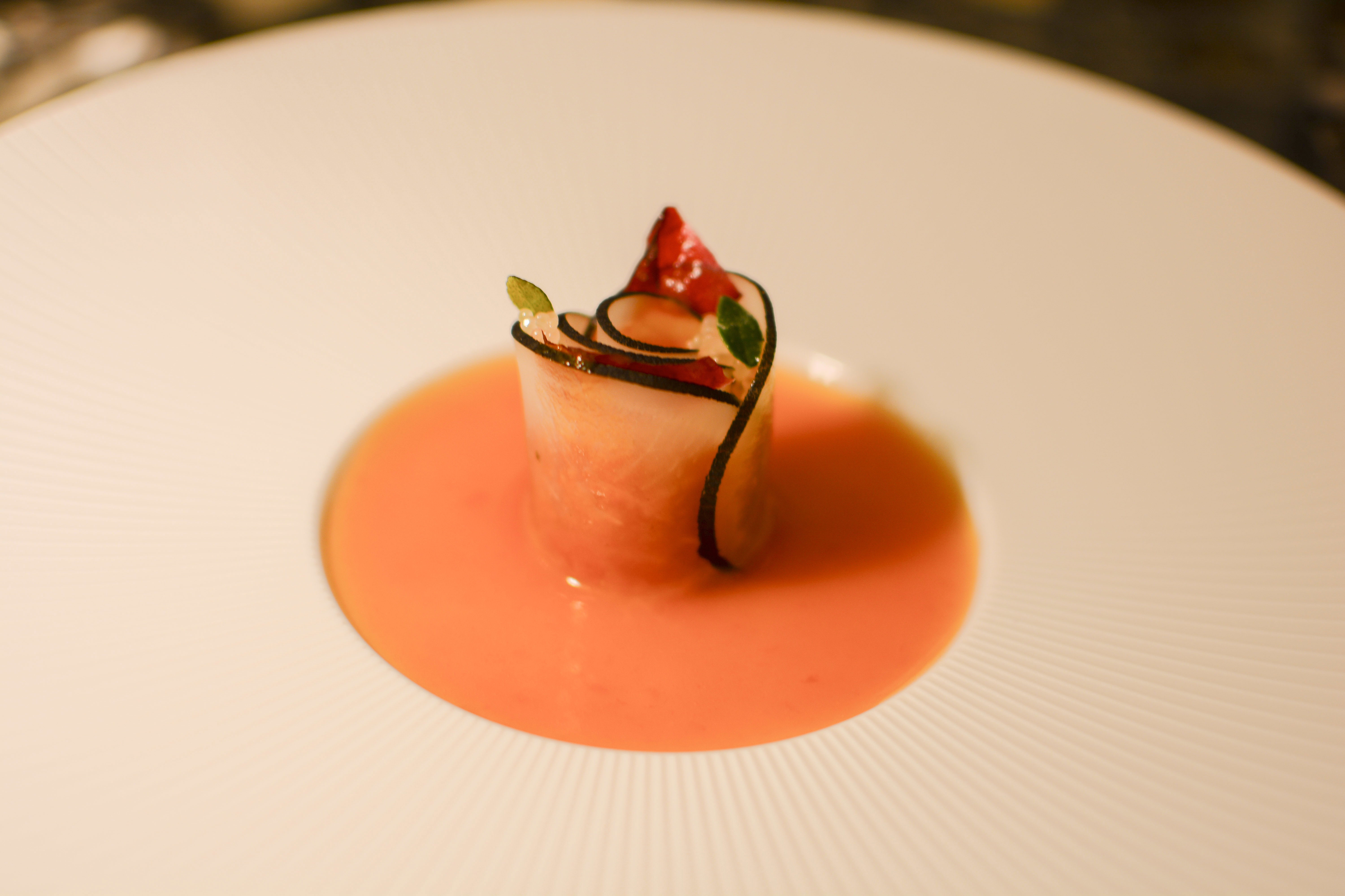 וורד של סשימי טונה עטוף בצנון שחור מקומי, על ויניגרט משמשים ועגבניות מותססות, עם פינגר ליים ועלי ורדים צלויים.