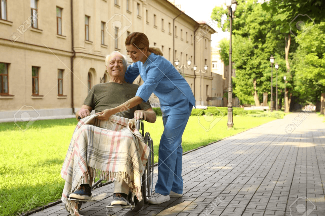 Happy Nurse Assisting Elderly Man In Wheelchair At Park Stock ...
