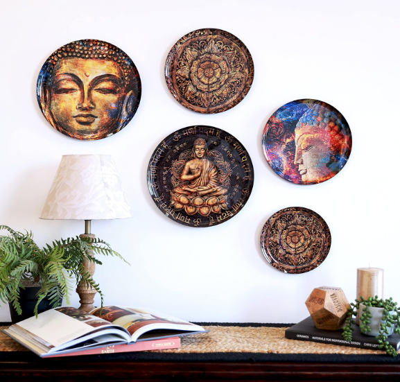 Wall plates arranged above a desk with books and a lamp, blending spiritual art with a modern workspace aesthetic.