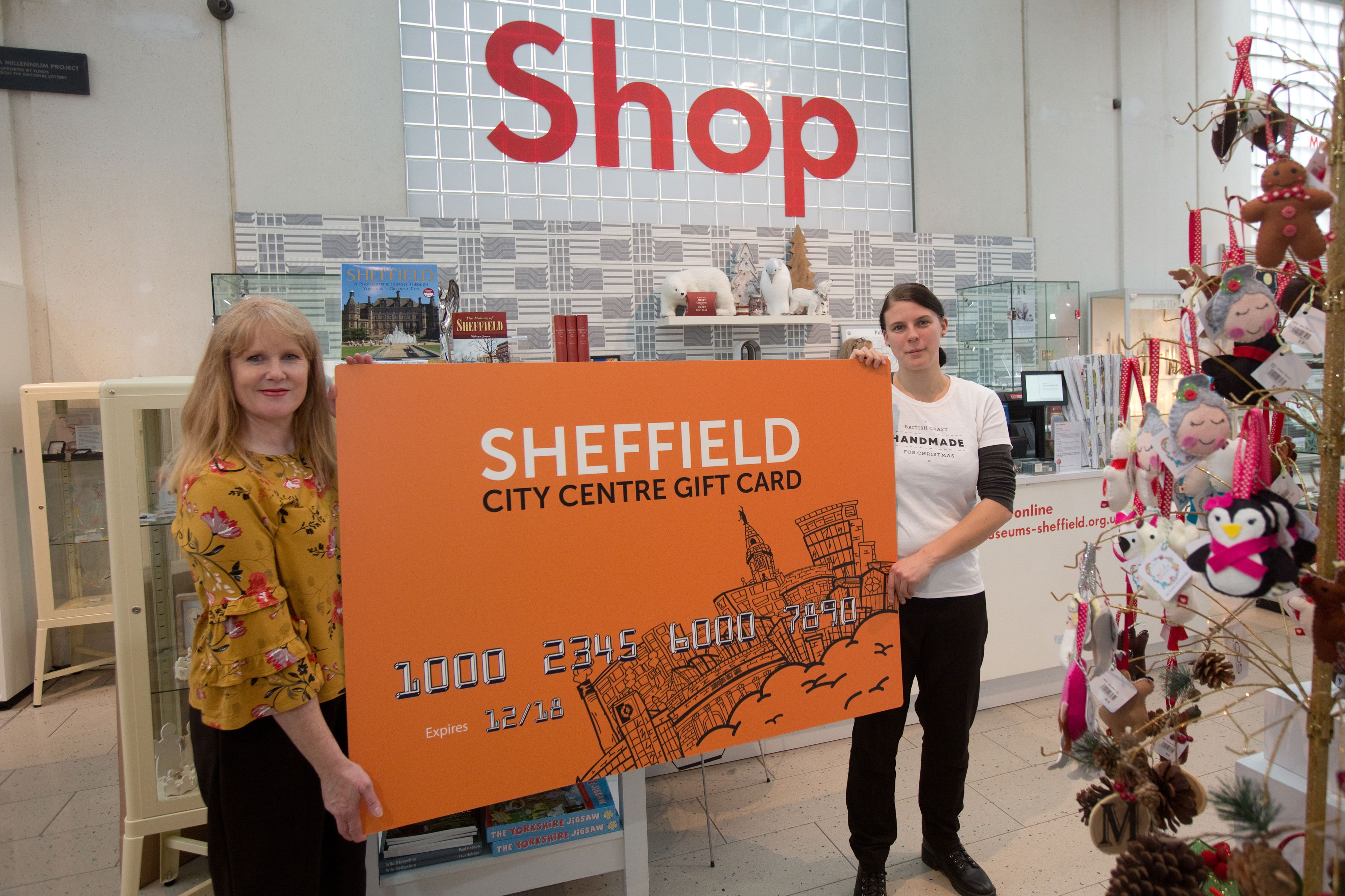 Two people holding a giant gift card to launch the Sheffield city centre gift card in 2017