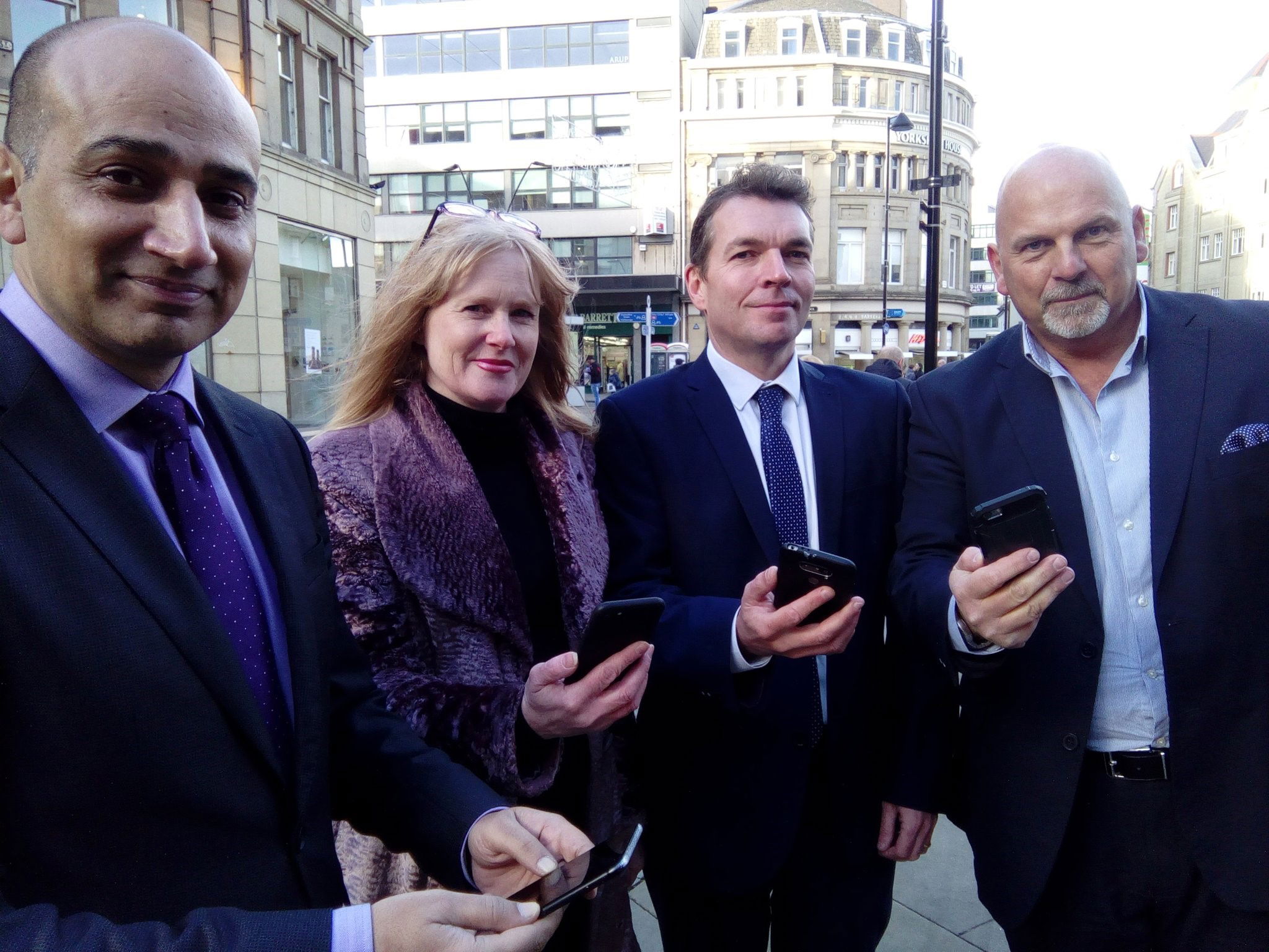 A group of business people holding mobile phones for the launch of Sheffield Free WIFI 