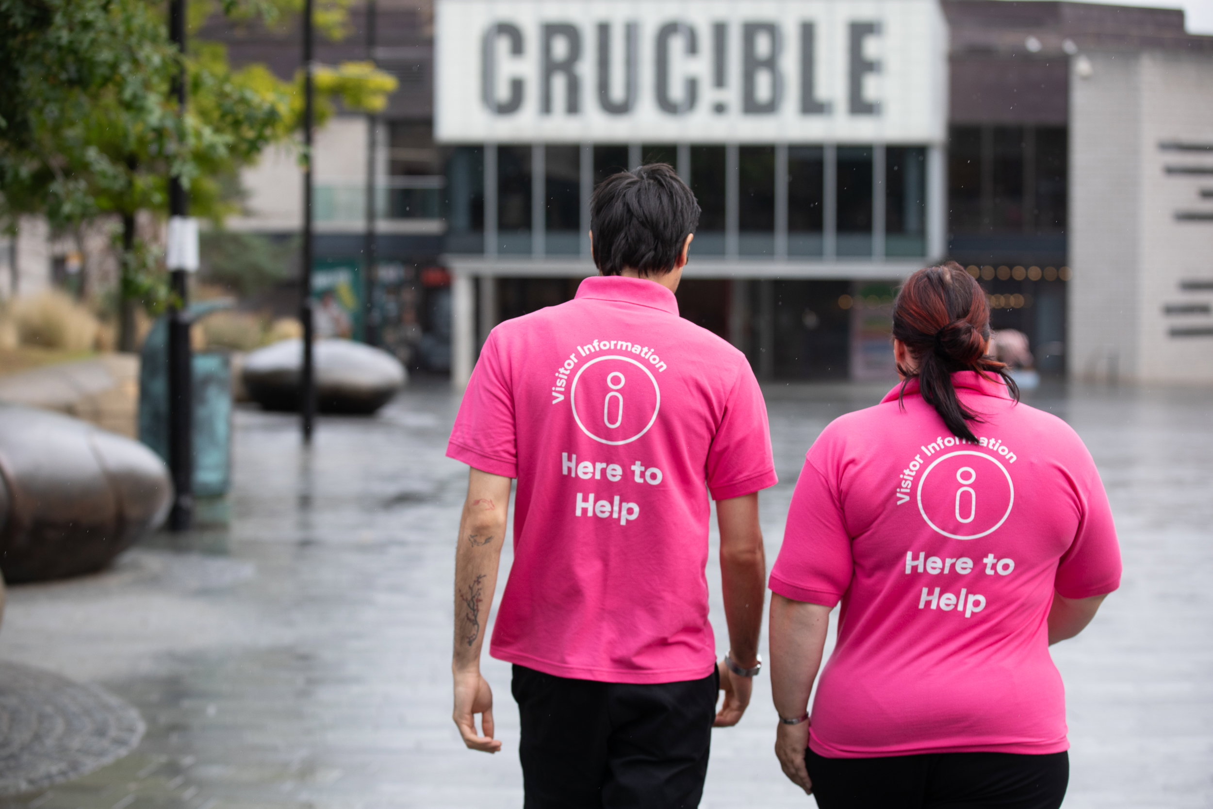A photograph of two of Sheffield BID's welcome team members walking towards the Crucible theatre