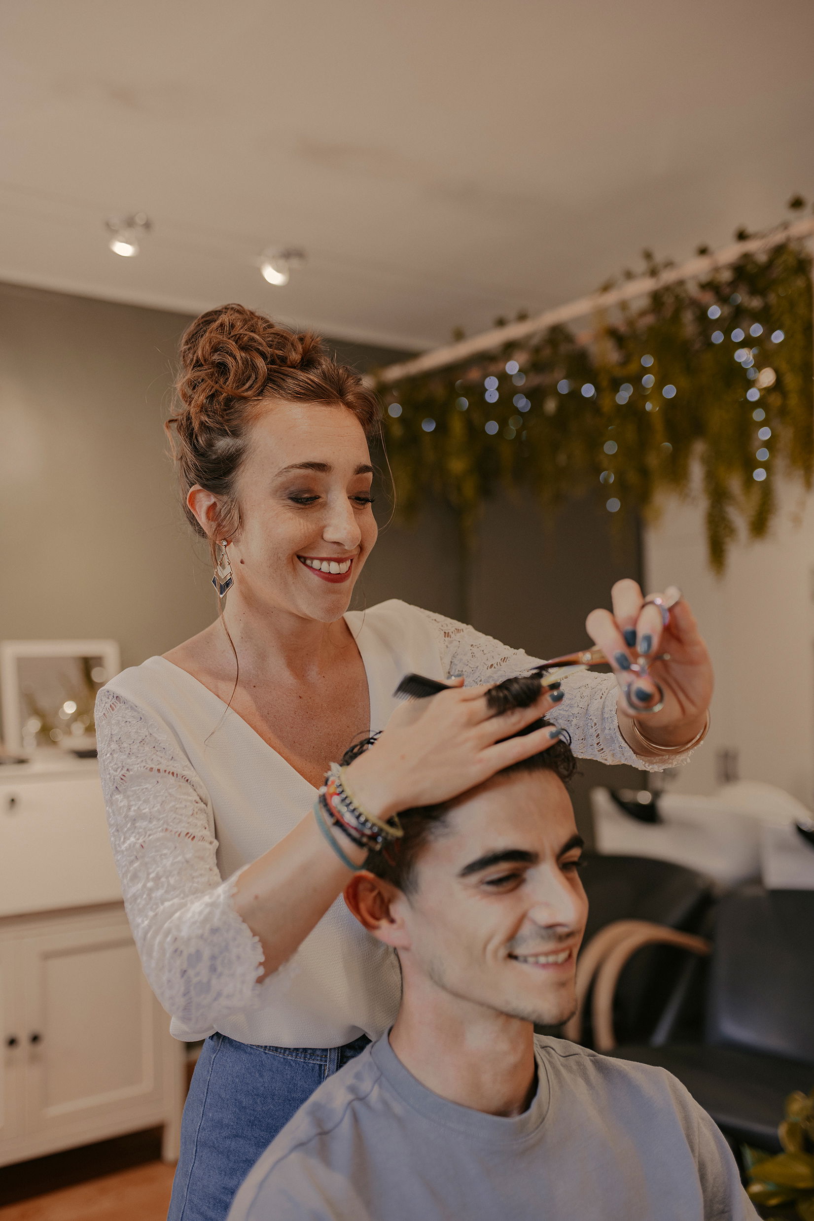 Anais Faure dans son salon de coiffure réalisant une coupe homme