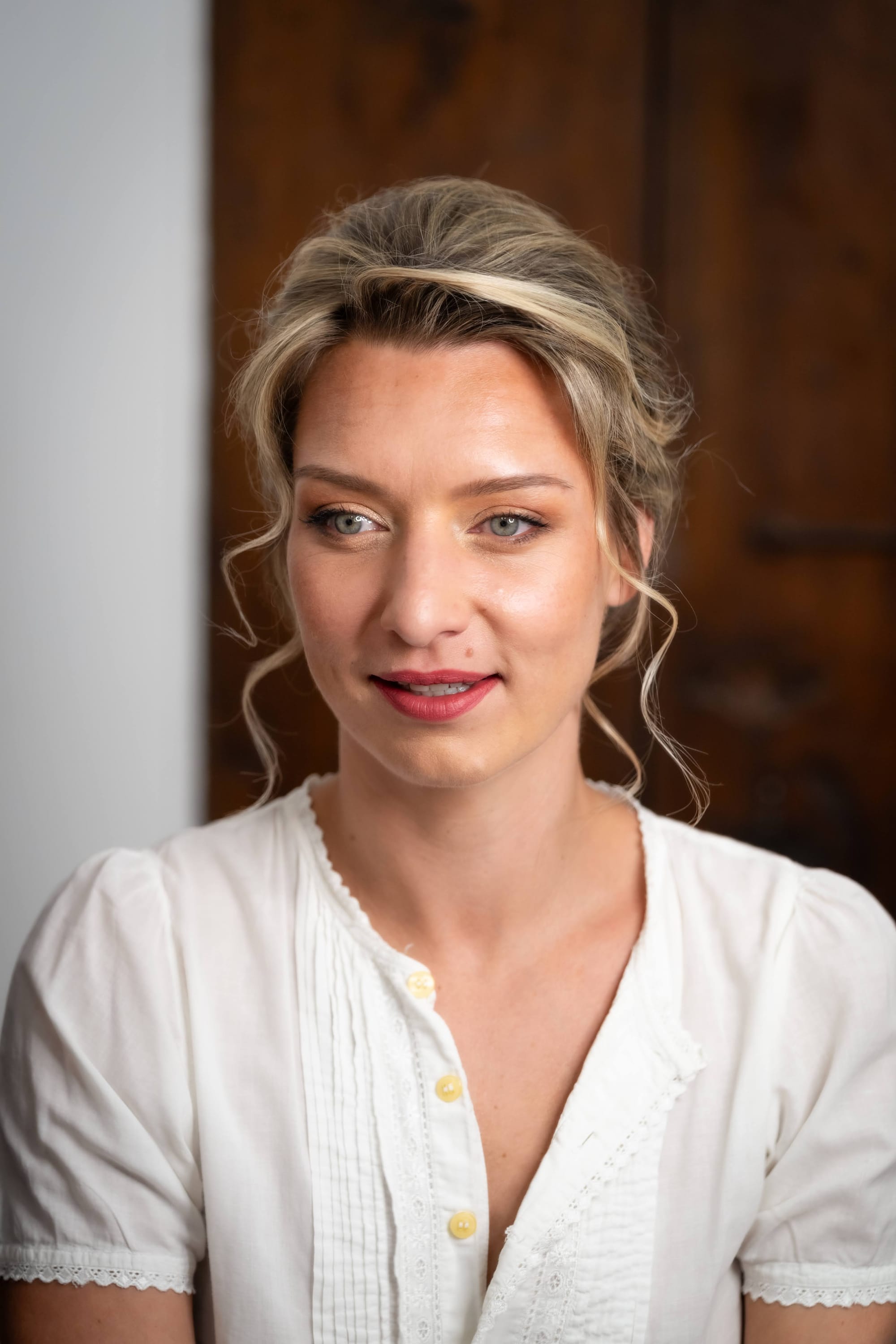 Mariée chignon ondulé avec fleurs naturelles, boucles souples autour du visage, maquillage naturel tons chauds