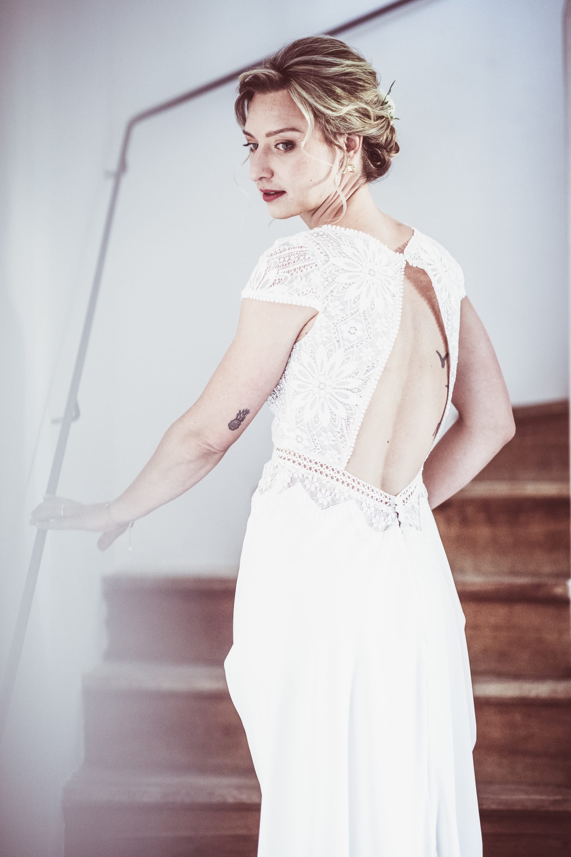 Mariée chignon ondulé avec fleurs naturelles, boucles souples autour du visage, maquillage naturel tons chauds