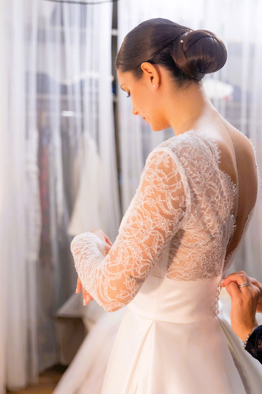 Mariée chignon bas chic avec perles, robe de mariée avec bustier manches longues décolleté dans le dos