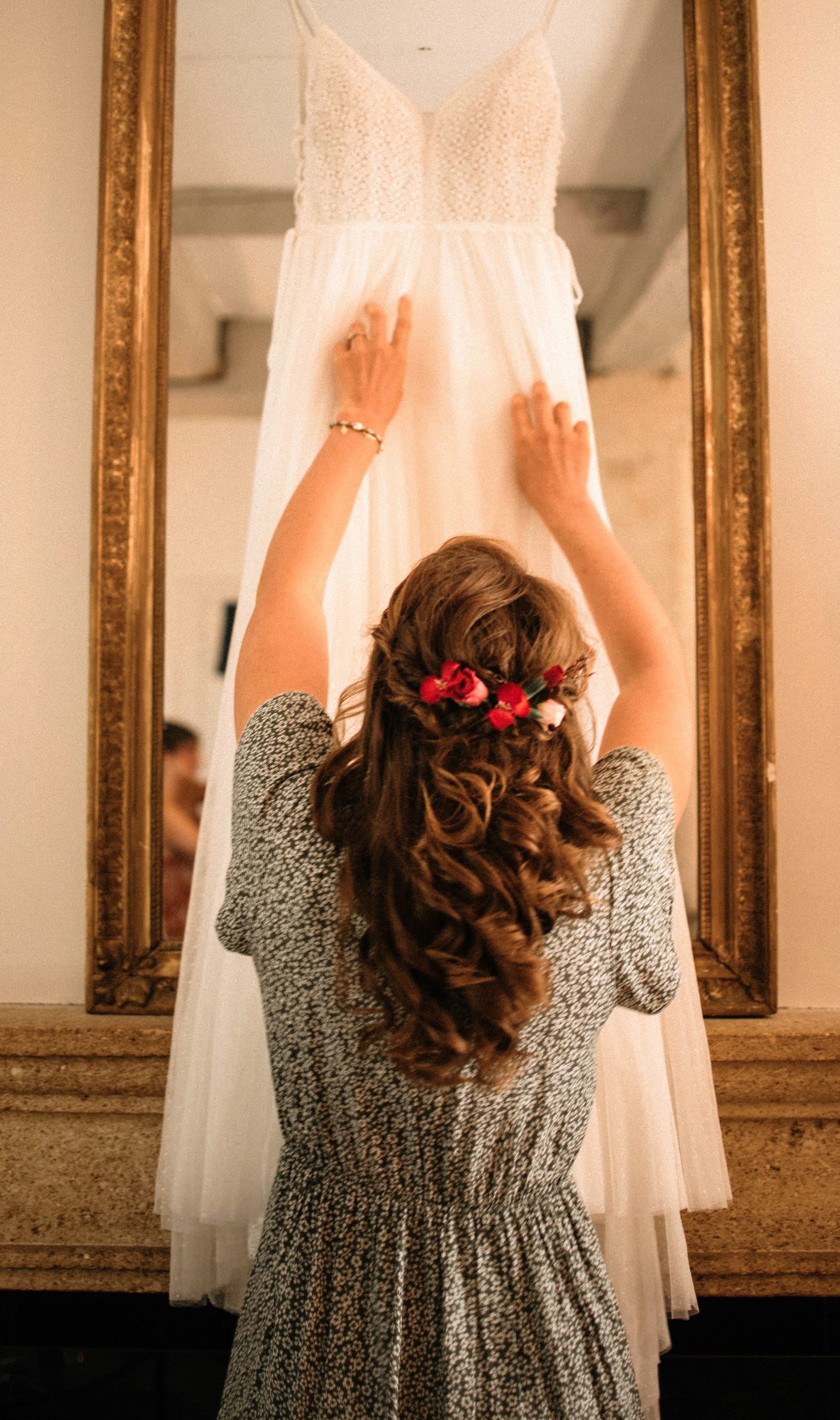 Coiffure de mariage cheveux longs et bouclés, roses rouges piquées dans les cheveux