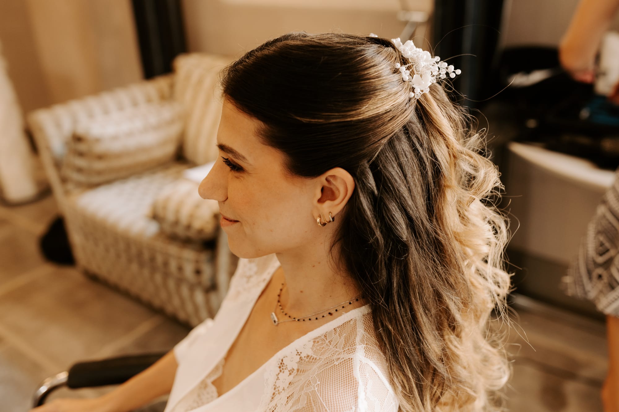 Coiffure mariée cheveux bouclés attachés en demi-queue avec un peigne en perles