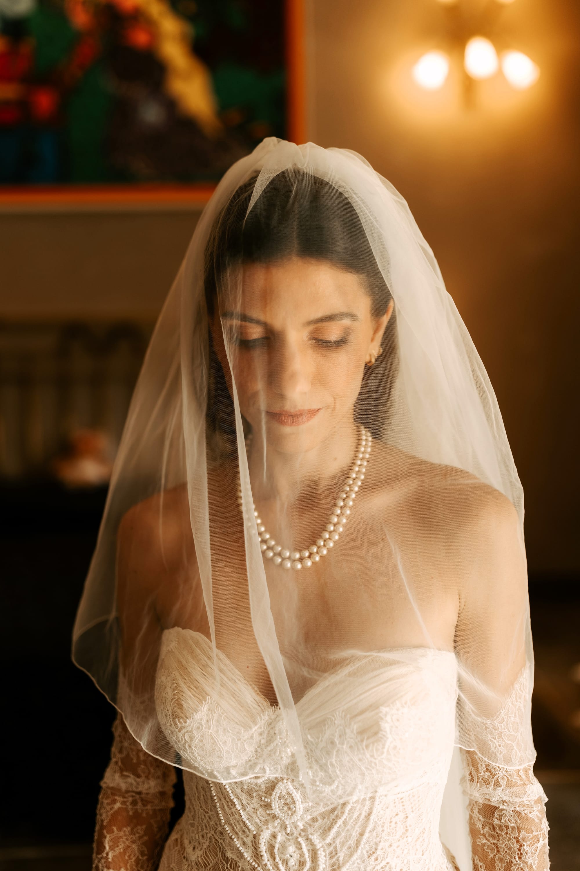 Mariée maquillage naturel rouge à lèvres brun terre cuite, voile, collier de perles et robe bustier drapée et dentelles, perles