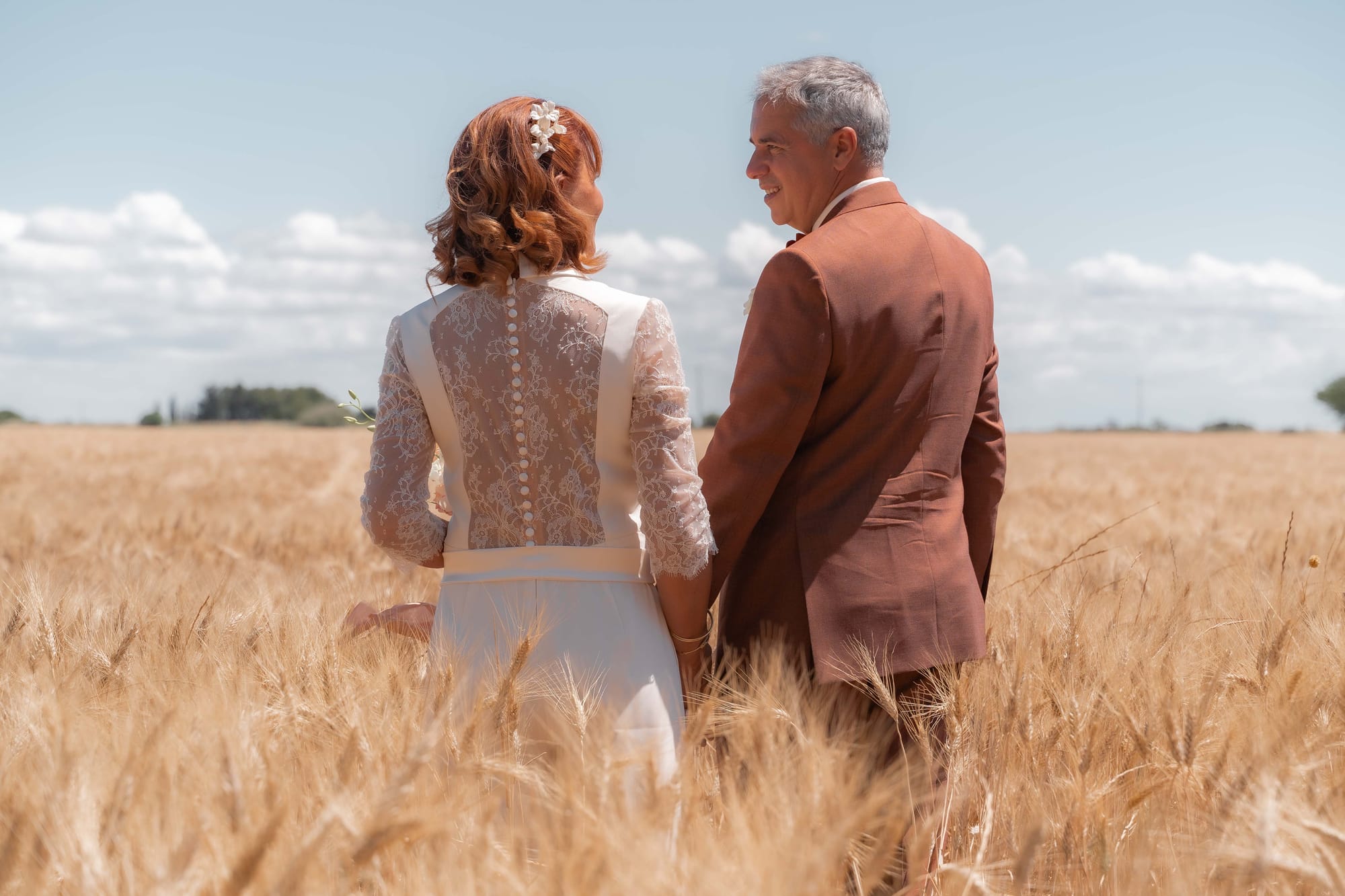 Marié costume marron, Mariée combinaison satin manches longues et dos dentelle avec boutons, cheveux roux mi-long ondulés avec barrette fleurs blanches