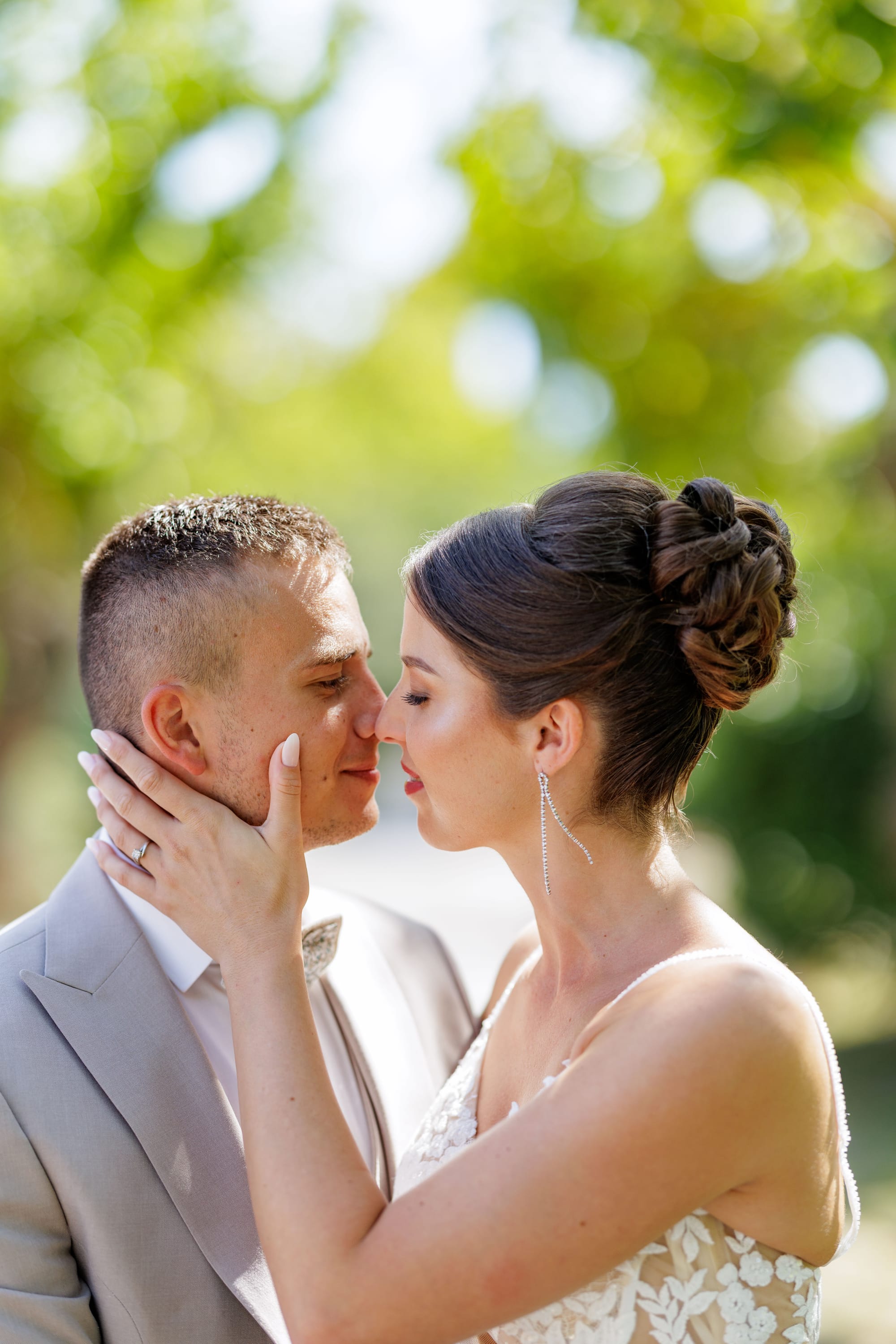 Coiffure de mariage chignon haut avec mèches torsadées, boucles d'oreilles strass, robe bustier dentelle
