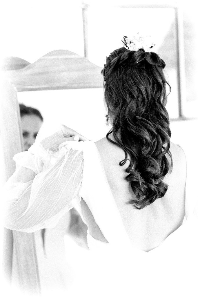 Mariée cheveux long bouclés, barrette fleurs sèches, robe dos plongeant manche en voile