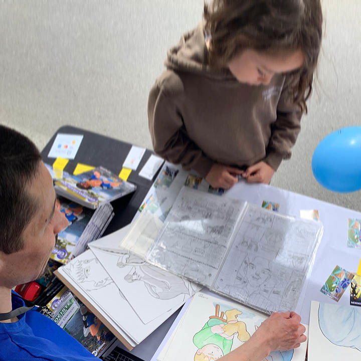 Un enfant montre ses premières bandes dessinées à Xavier Crespo