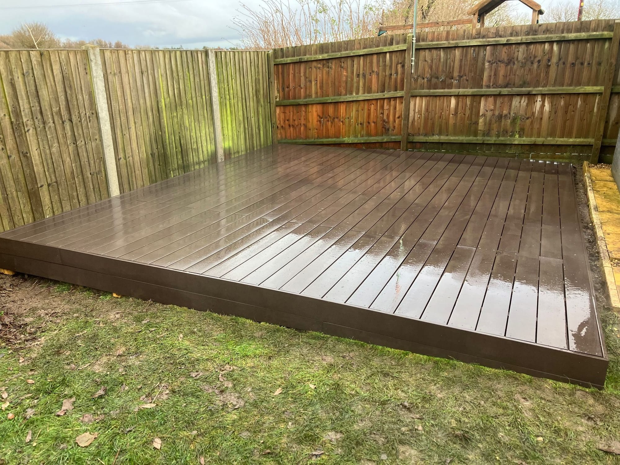 Raised composite decking section to corner of back garden to create additional large seating and dining area