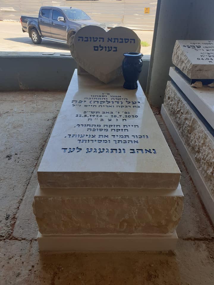 מצבה בודדת בגוונים חמים עם כרית בגוון תואם ובסמוך אליה כד שחור תואם