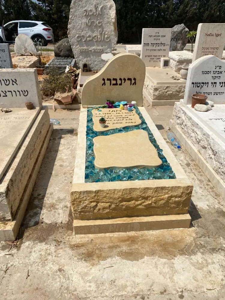 מצבה משפחתית מעוצבת מאבן בגוונים חמים וגבישי זכוכית בירוק