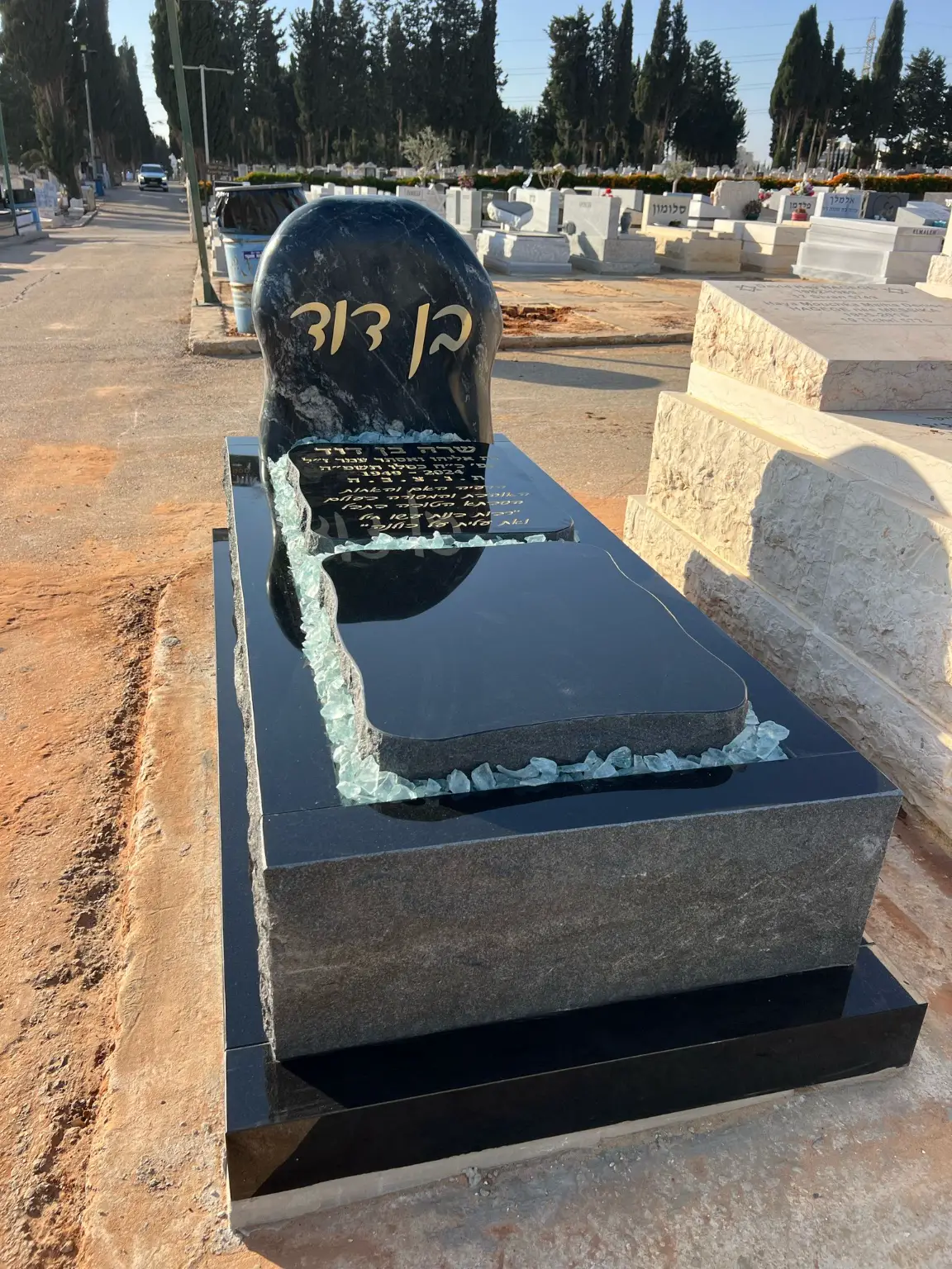 מצבה משפחתית מעוצבת מגרניט שחור, גבישי זכוכית בירוק בהיר וכיתוב אותיות זהב