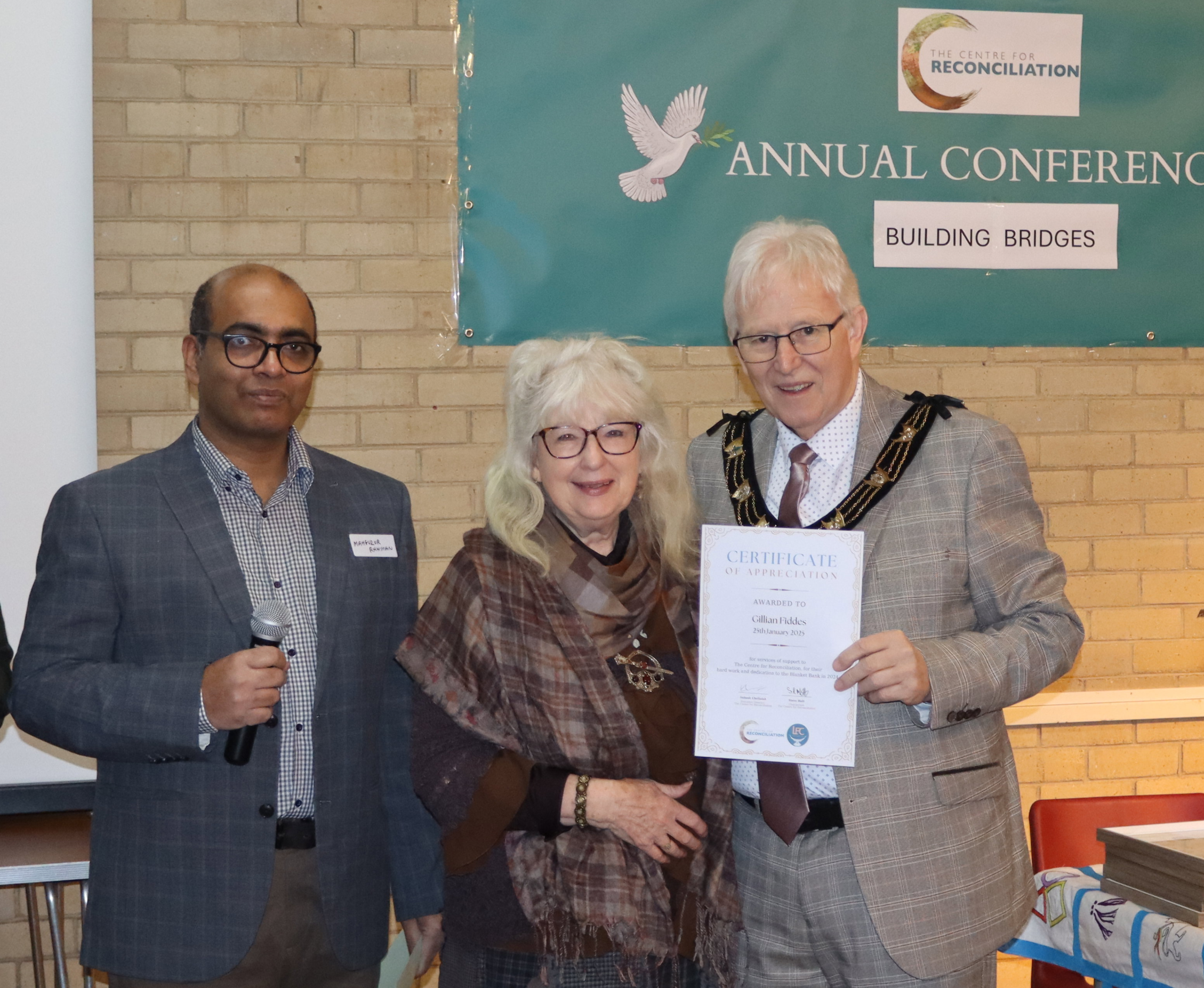 Gillian Fiddes receives a certificate of appreciation for her knitting contributions from the then Mayor of Lincoln, Alan Briggs, at TCfR’s 2025 Annual General Meeting.