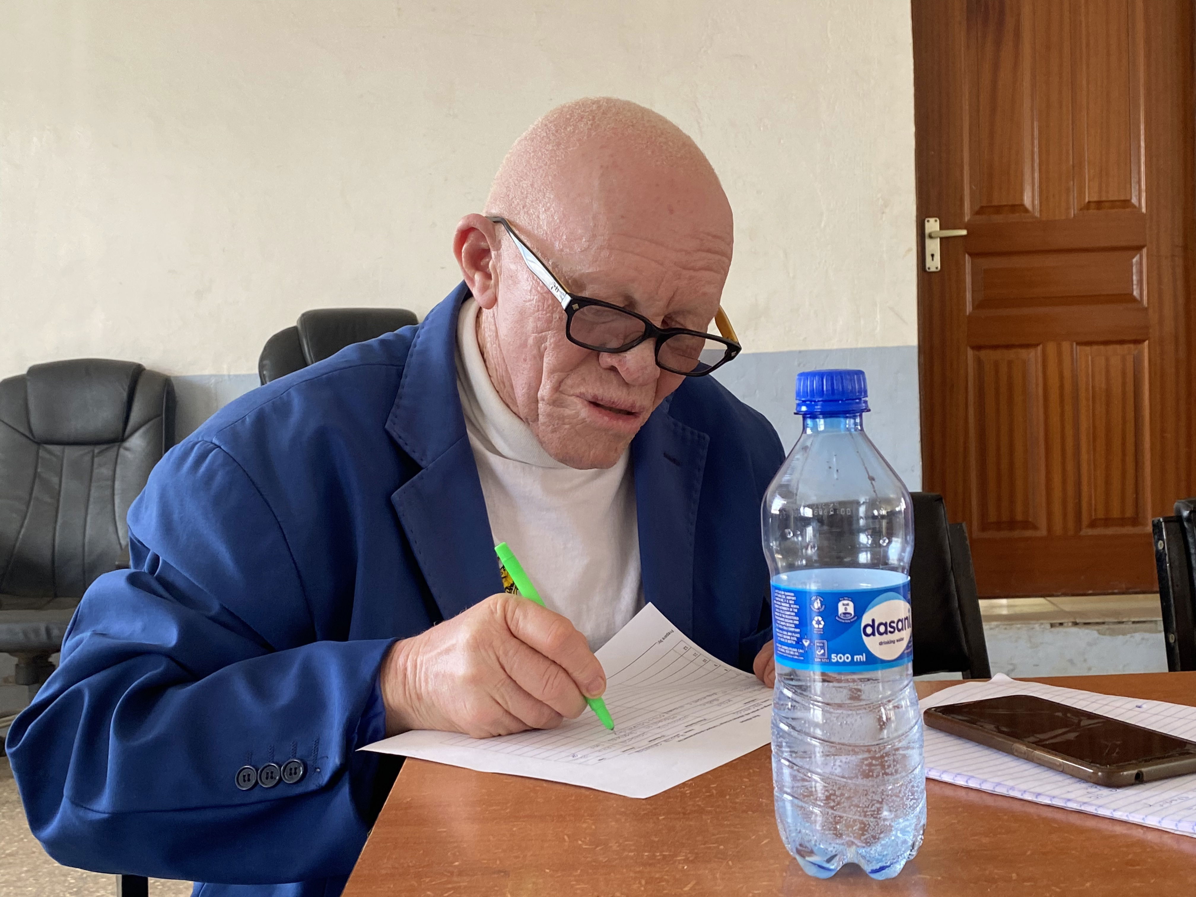 A person with albinism fills out a form during a focus discussion group about climate change in Machakos County.